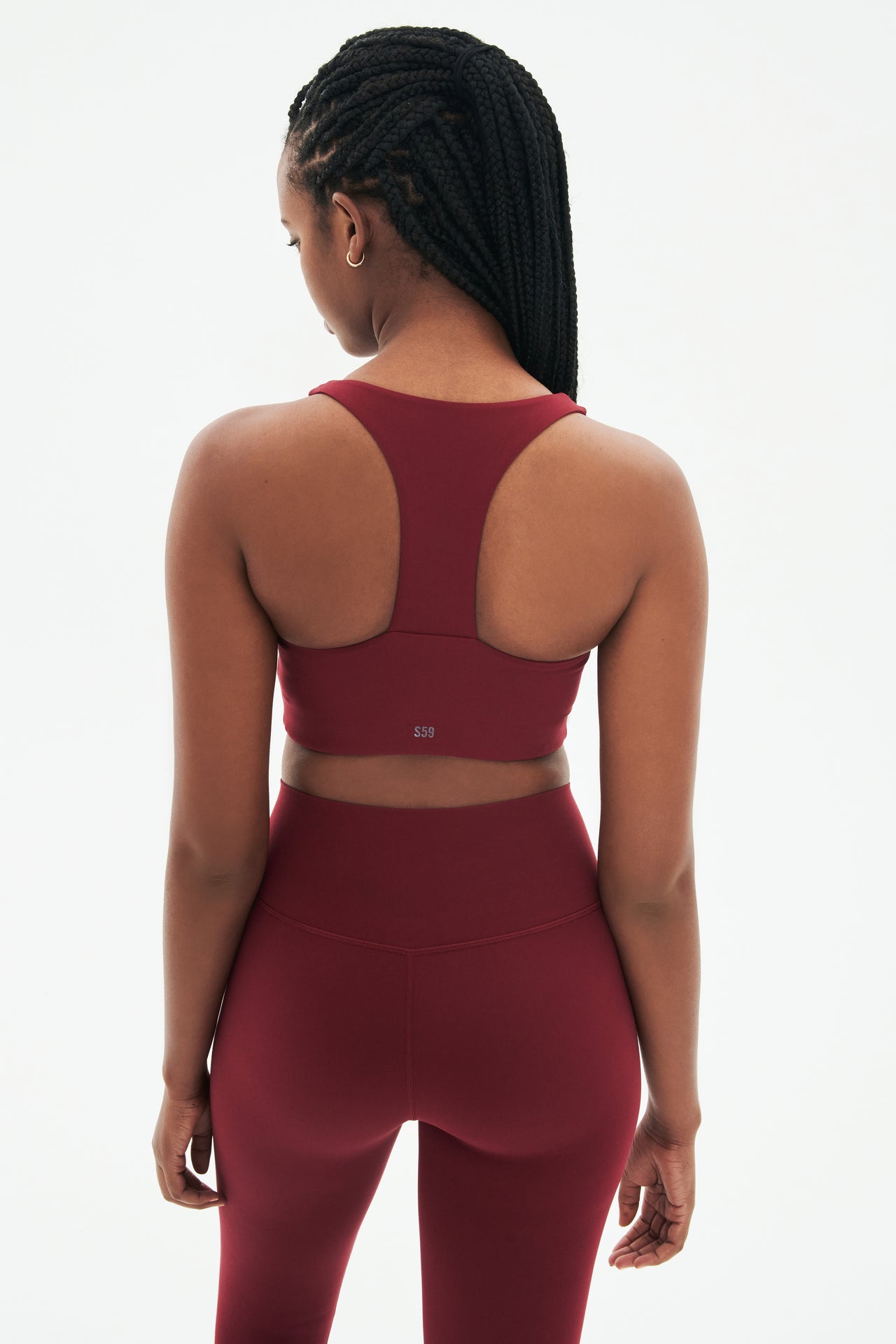 Back view of woman with black braids wearing dark red bra with racerback and dark red leggings