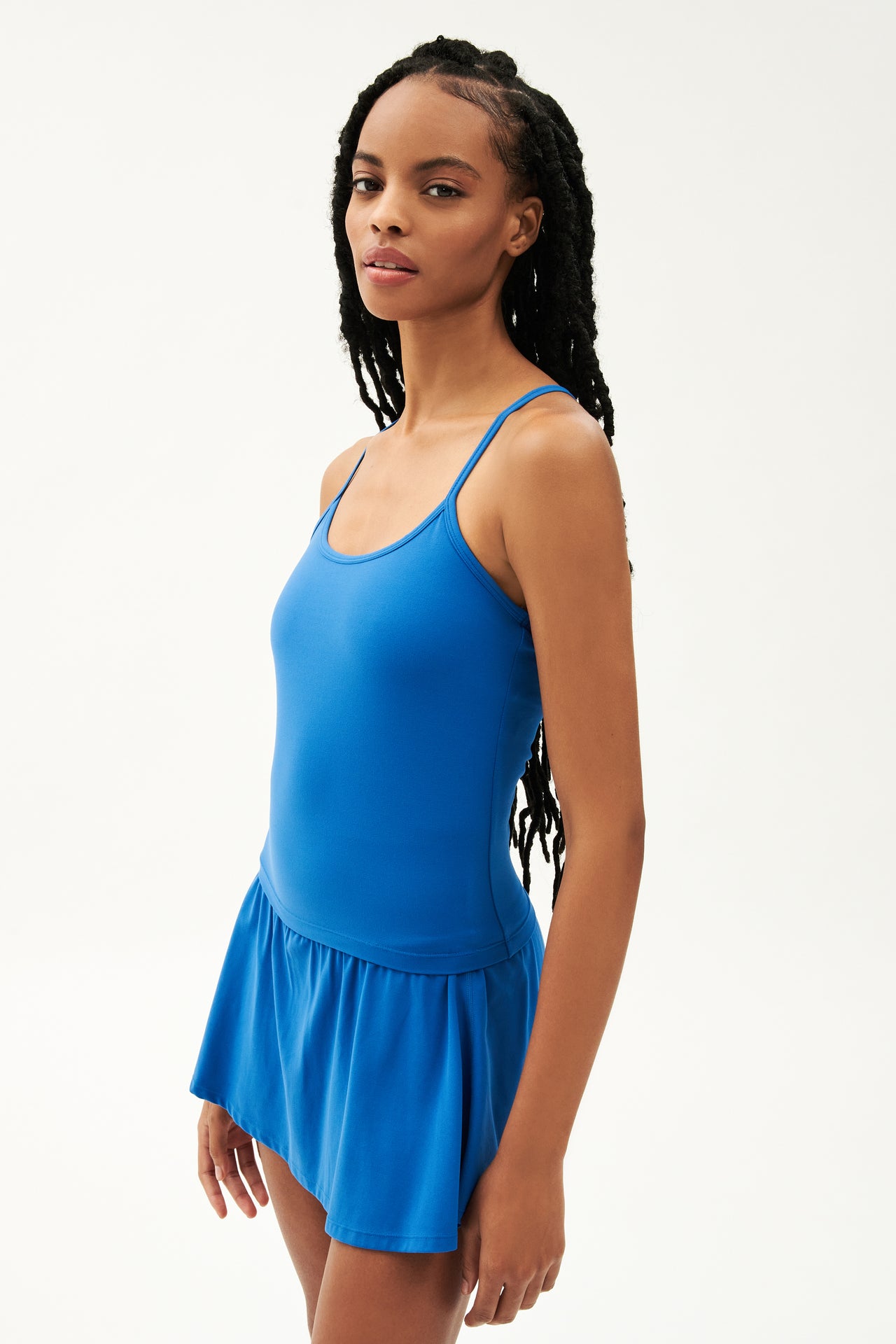 Side view of girl wearing blue spaghetti strap tank top with blue skirt