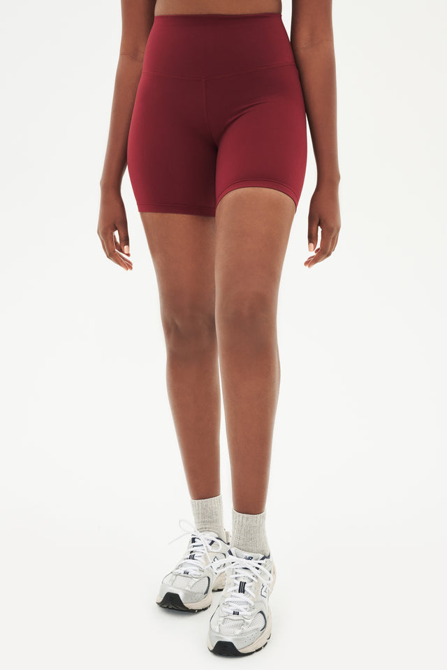 Front view of girl wearing highwaisted mid thigh deep bike shorts with white shoes