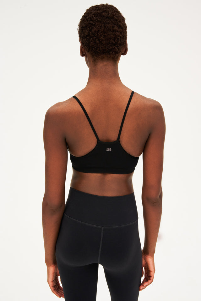 The back view of a woman wearing black leggings and a SPLITS59 Loren Bra Bundle.