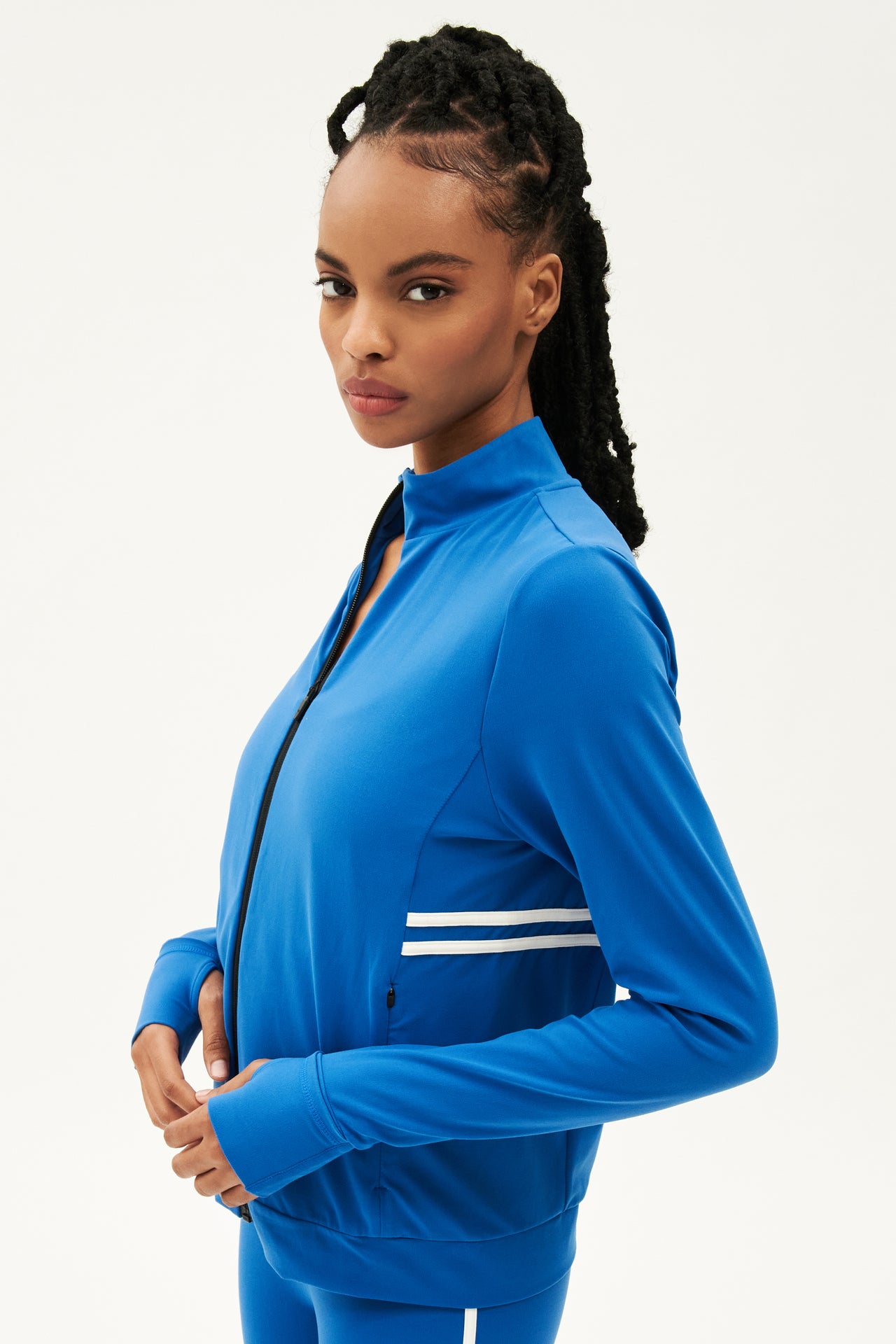 A woman wearing a SPLITS59 Rain Airweight Jacket in Classic Blue/White and leggings heads to her hot yoga class.