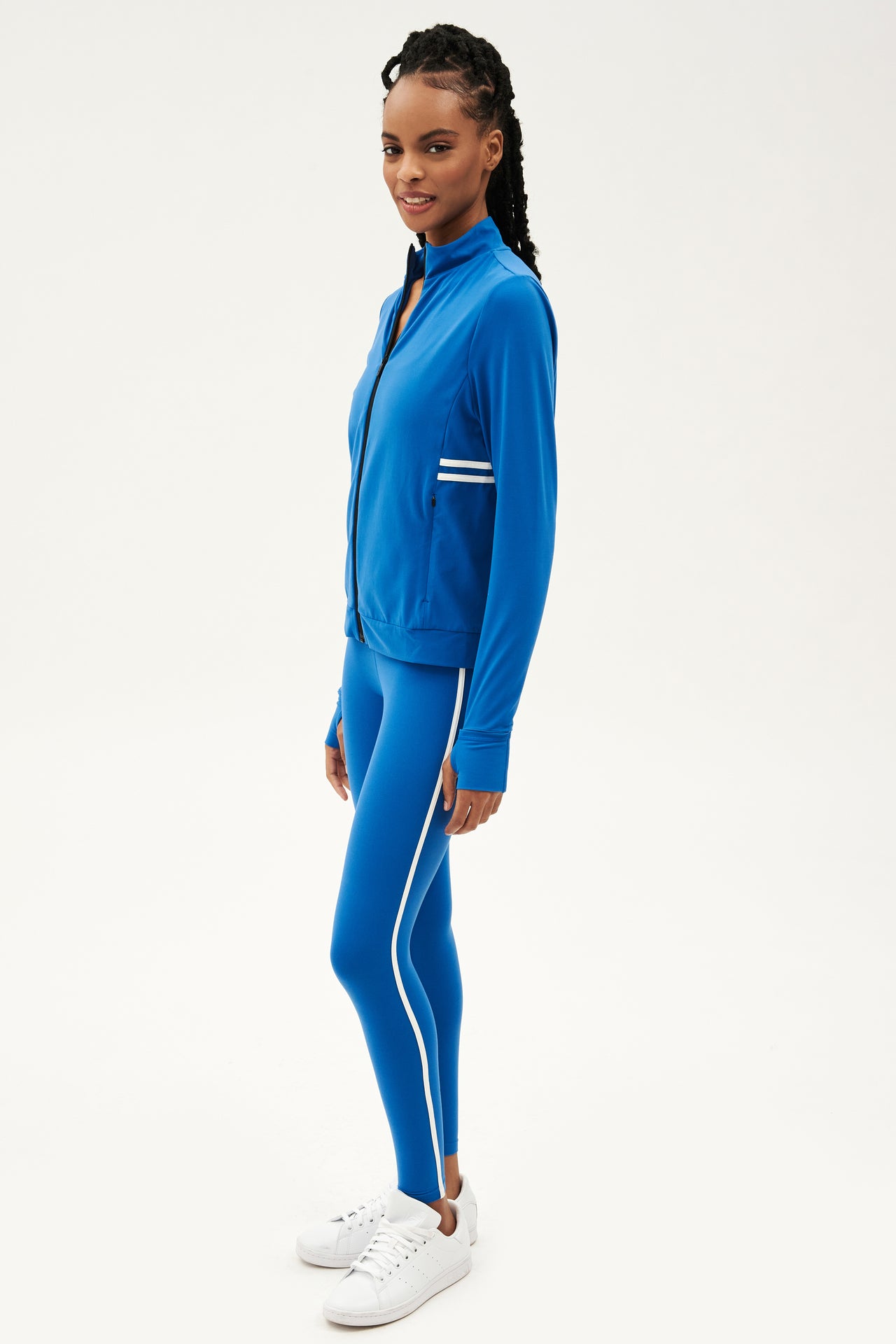 A woman wearing a SPLITS59 Rain Airweight Jacket in Classic Blue and white leggings suitable for barre.