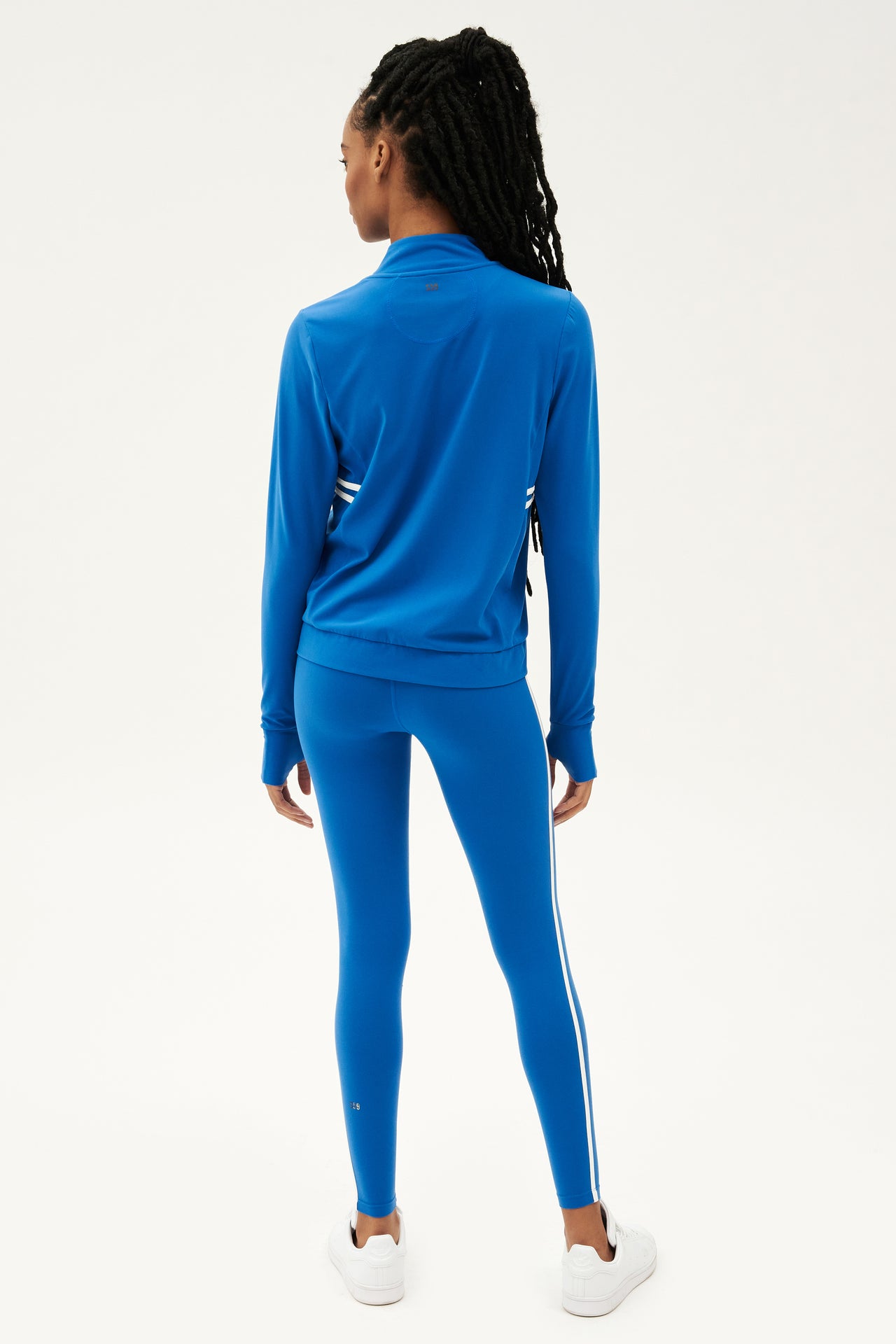 The back view of a woman in a SPLITS59 Rain Airweight Jacket - Classic Blue/White, ready for a hot yoga session.