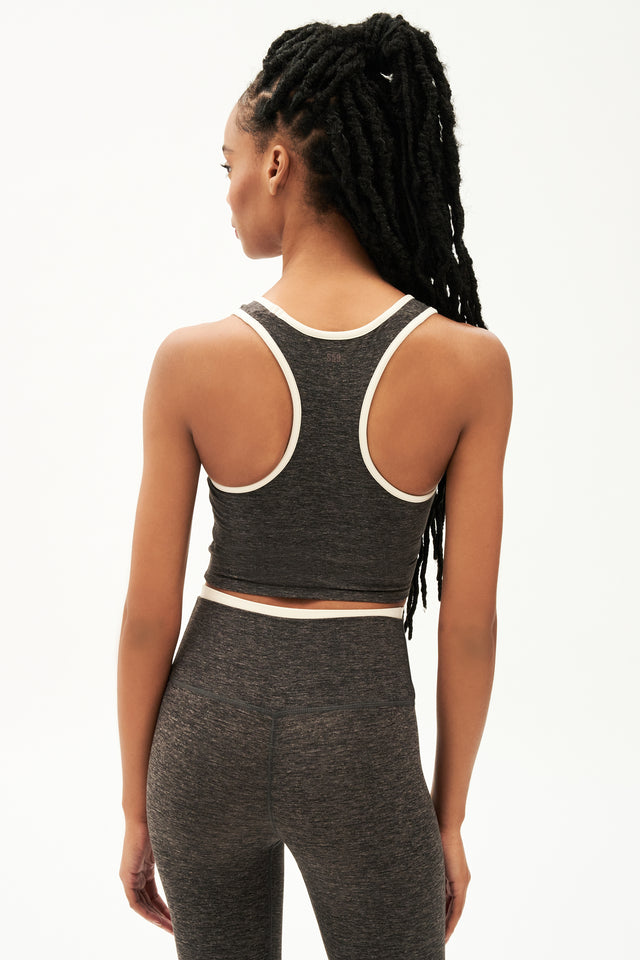 Back view of girl wearing cropped grey tank top with white trim and grey leggings with a thin white waistband
