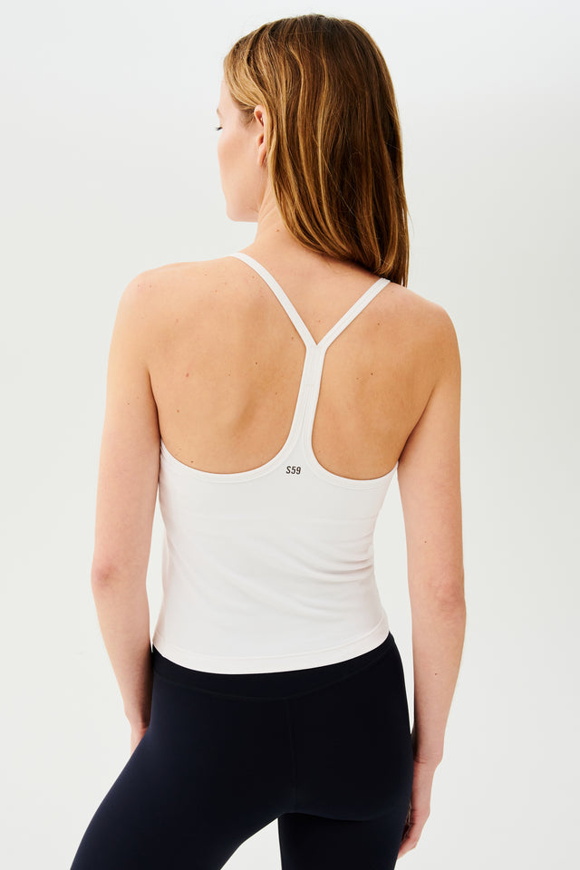 Back view of girl wearing white spaghetti strap tank top with black leggings