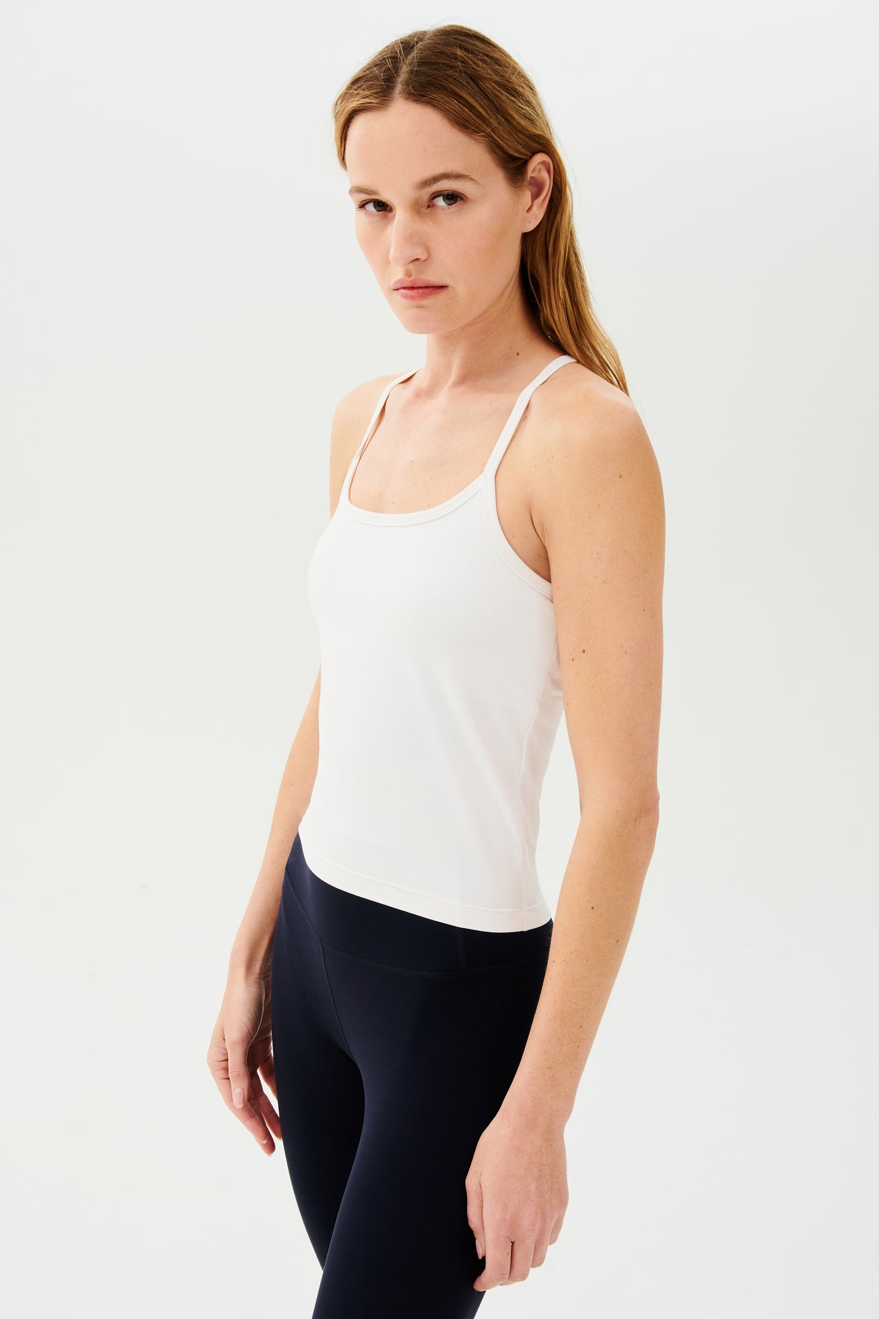 Front view of girl wearing white spaghetti strap tank top with black leggings
