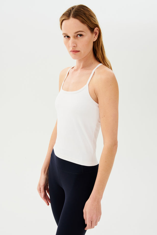Front view of girl wearing white spaghetti strap tank top with black leggings