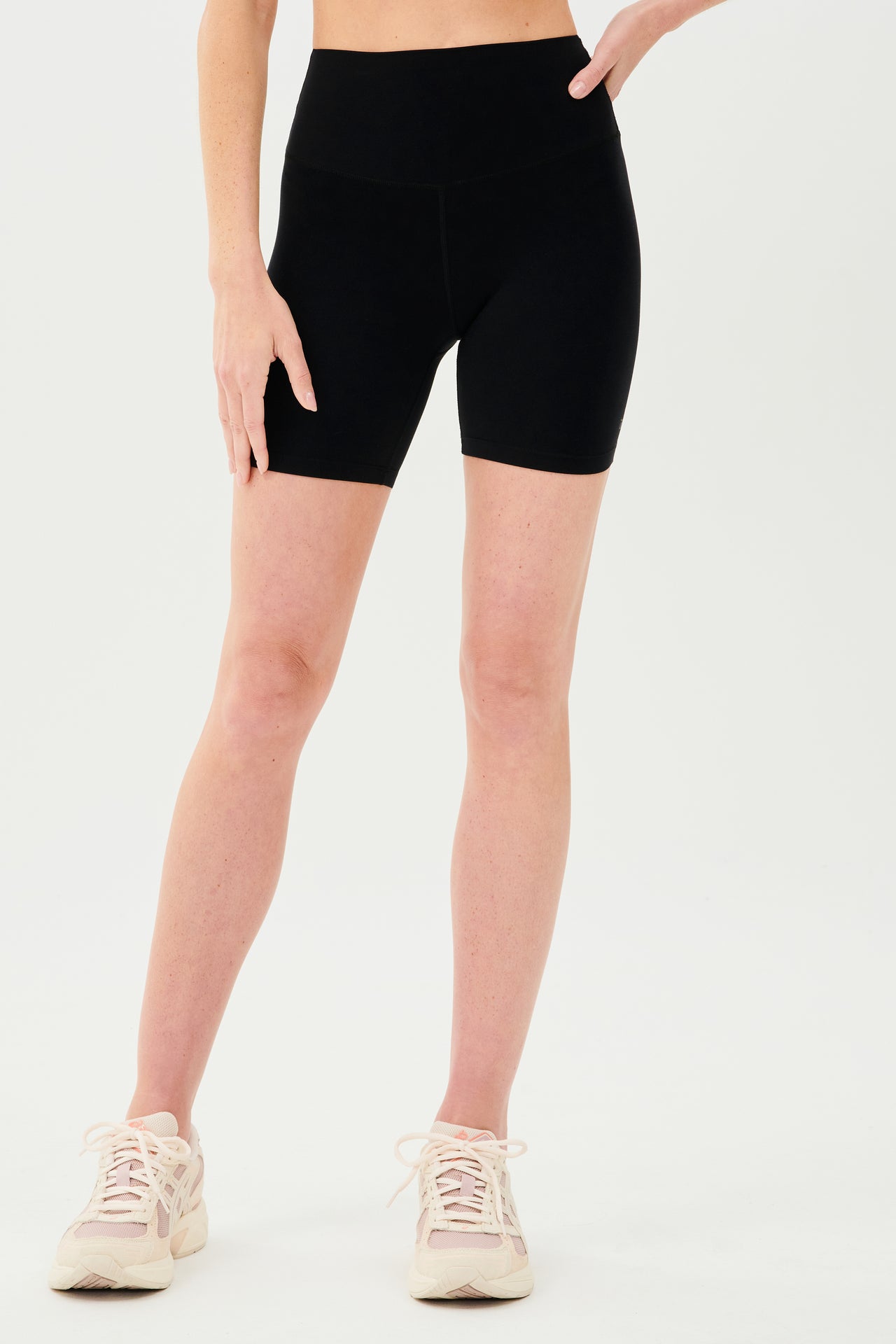 Front view of girl wearing highwaisted mid thigh black bike shorts with white shoes