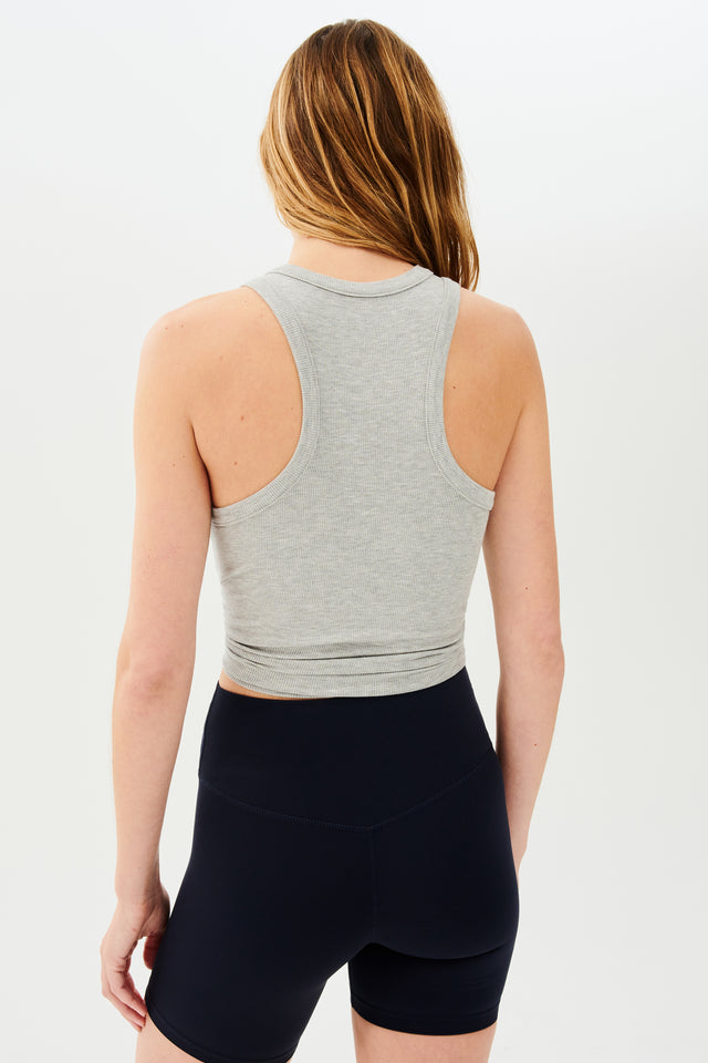 The back view of a woman wearing black shorts and a SPLITS59 Kiki Rib Tank Full Length in Heather Grey for yoga.