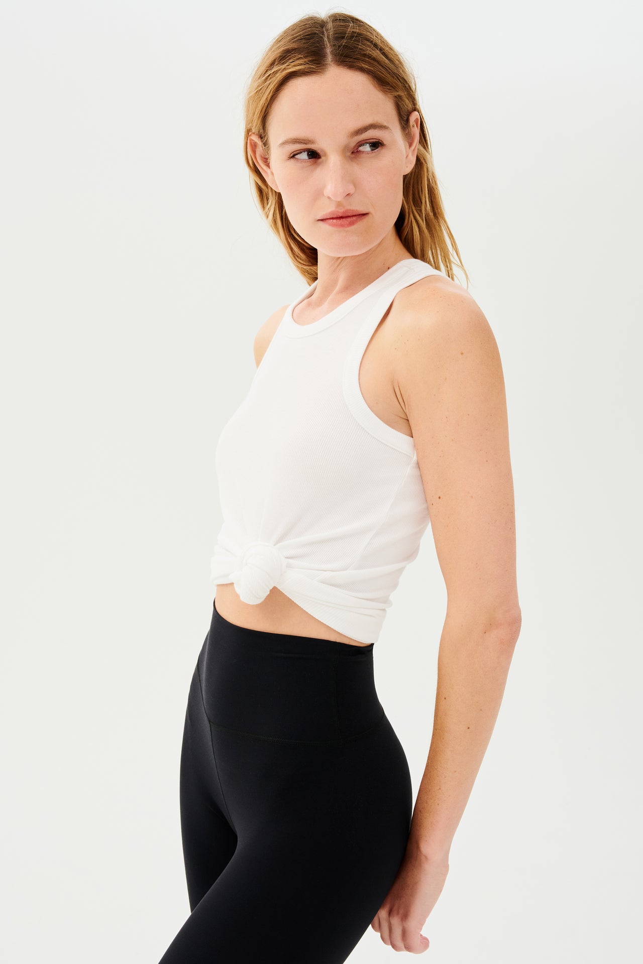 A woman wearing black leggings and a SPLITS59 Kiki Rib Tank Full Length in white for gym workouts.