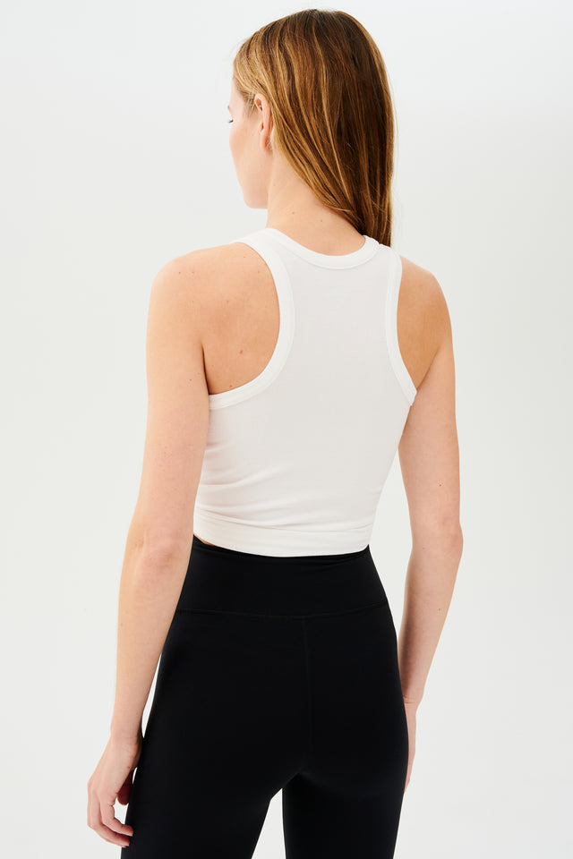 The back view of a woman wearing black yoga leggings and a SPLITS59 Kiki Rib Tank Full Length in White.