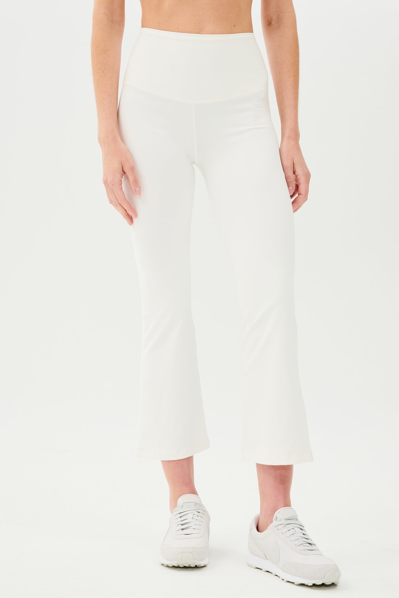 A woman wearing SPLITS59's Raquel High Waist Crop - White pants and a white tee designed for workout with 4-way stretch.