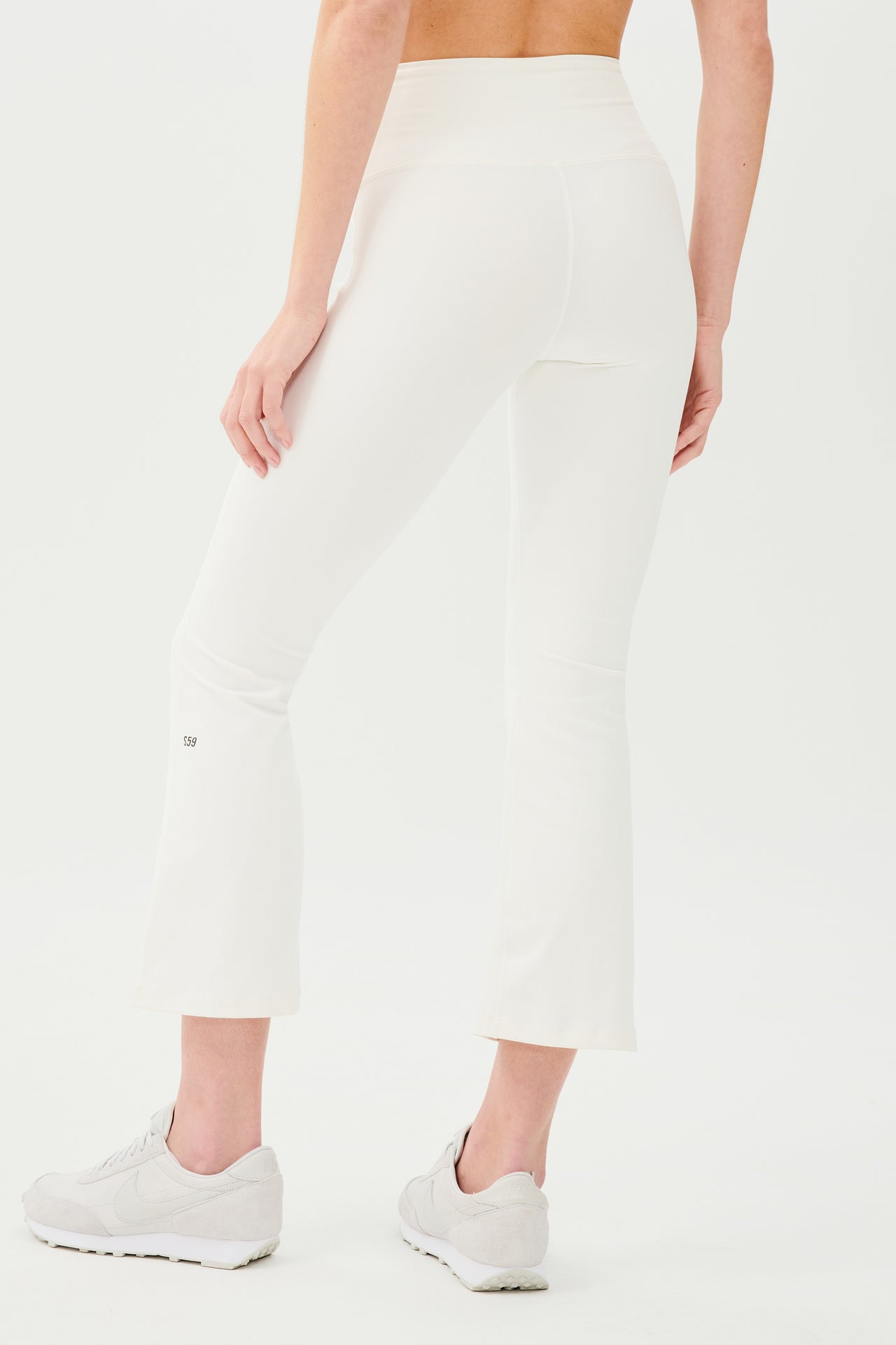 The back view of a woman wearing SPLITS59 Raquel High Waist Crop - White yoga pants with 4-way stretch.