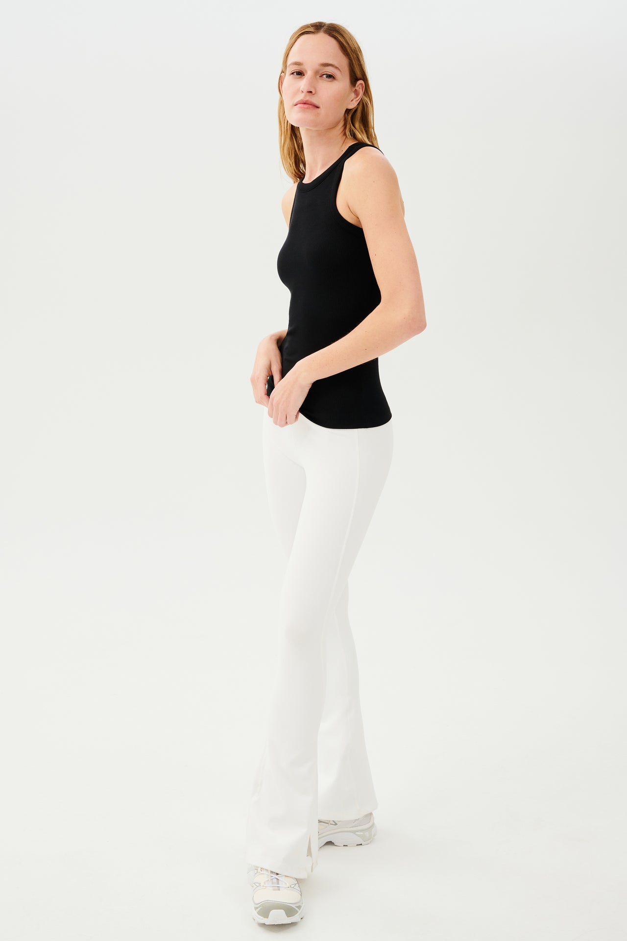 A woman wearing a SPLITS59 Kiki Rib Tank Full Length in Black and white pants, ready for her yoga session.