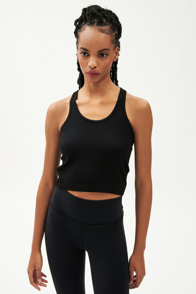 Front view of girl wearing a ribbed black cropped tank top and black leggings