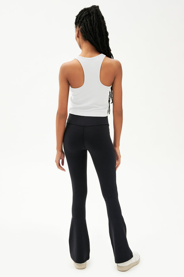 Full view of girl wearing a white cropped tank top and black leggings with white shoes