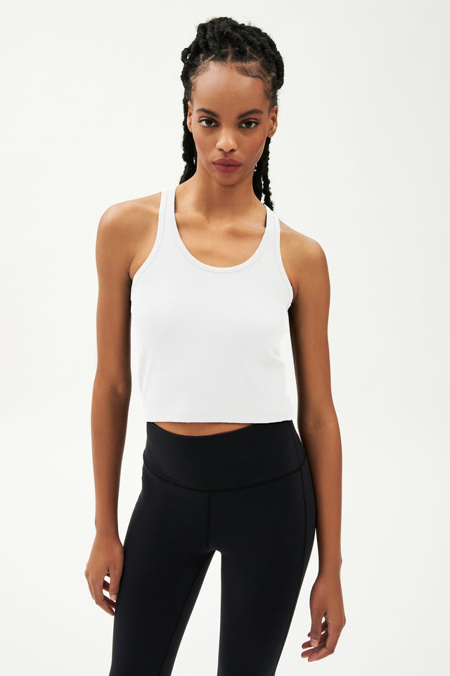 Front view of girl wearing a white cropped tank top and black leggings