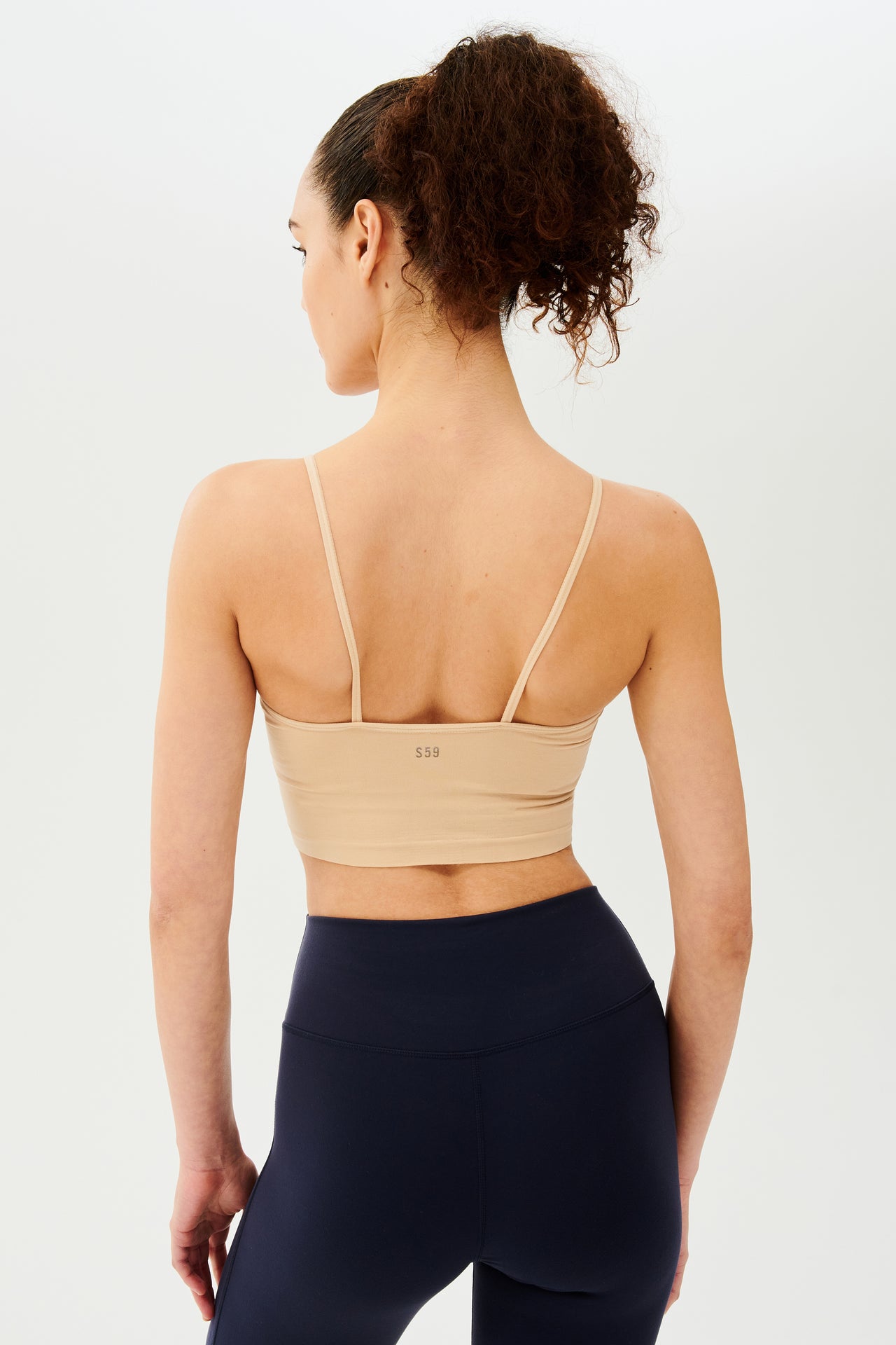 The back view of a woman wearing a Splits59 Loren Seamless Cami - Nude with chafe-free fabric.