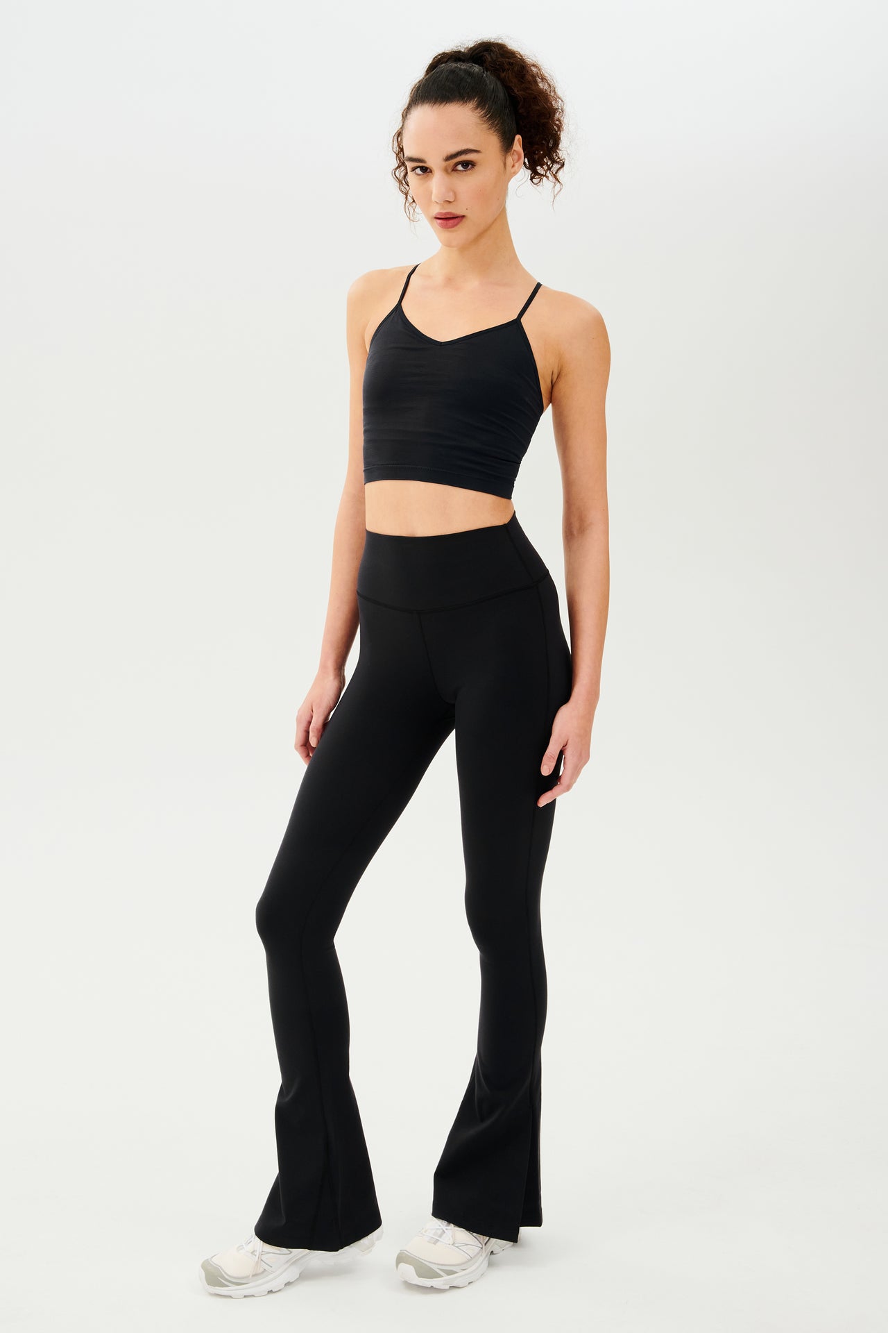 A woman wearing black leggings and a Splits59 Loren Seamless Cami - Black with a built-in shelf bra.