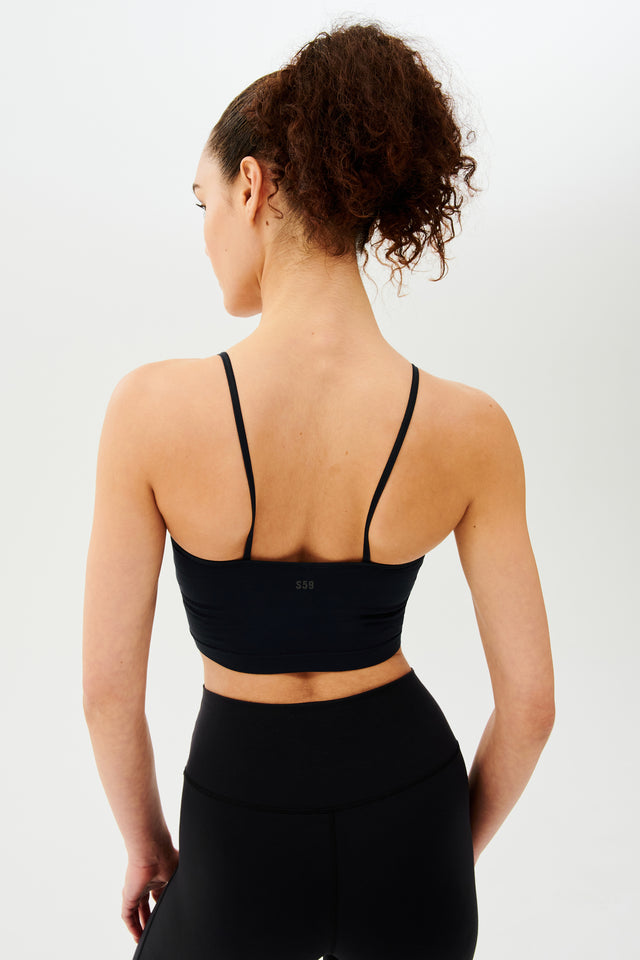 The back view of a woman wearing black leggings and a Splits59 Loren Seamless Cami - Black with a built-in shelf bra.
