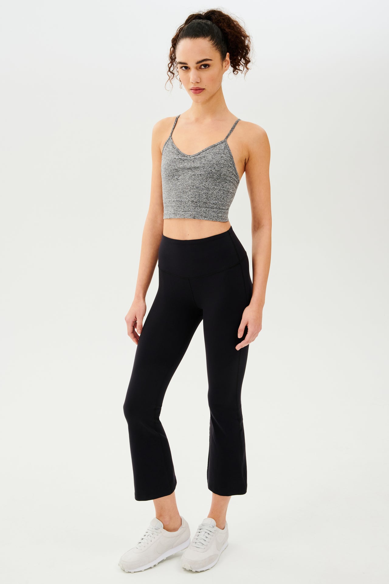 A woman wearing black leggings and a Splits59 Loren Seamless Cami - Heather Grey with a built-in shelf bra.
