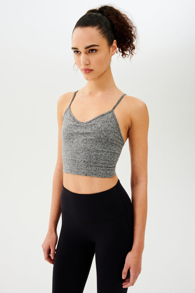 A woman wearing a Splits59 Loren Seamless Cami in Heather Grey with a built-in shelf bra and black leggings.