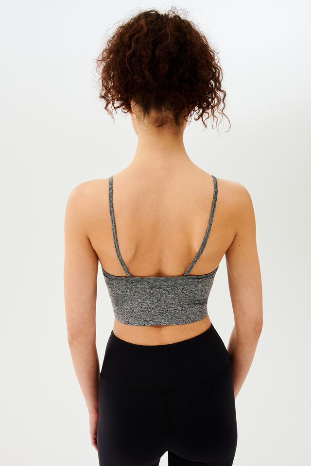The back view of a woman wearing black leggings and a Splits59 Loren Seamless Cami - Heather Grey with a built-in shelf bra.