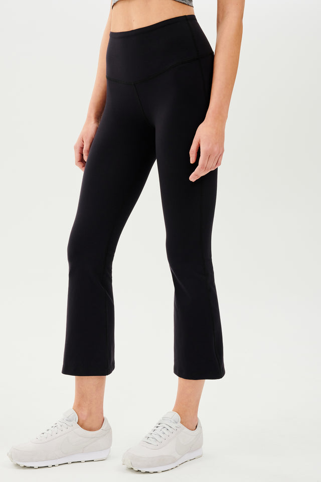 The back view of a woman wearing SPLITS59's Raquel High Waist Crop - Black leggings.