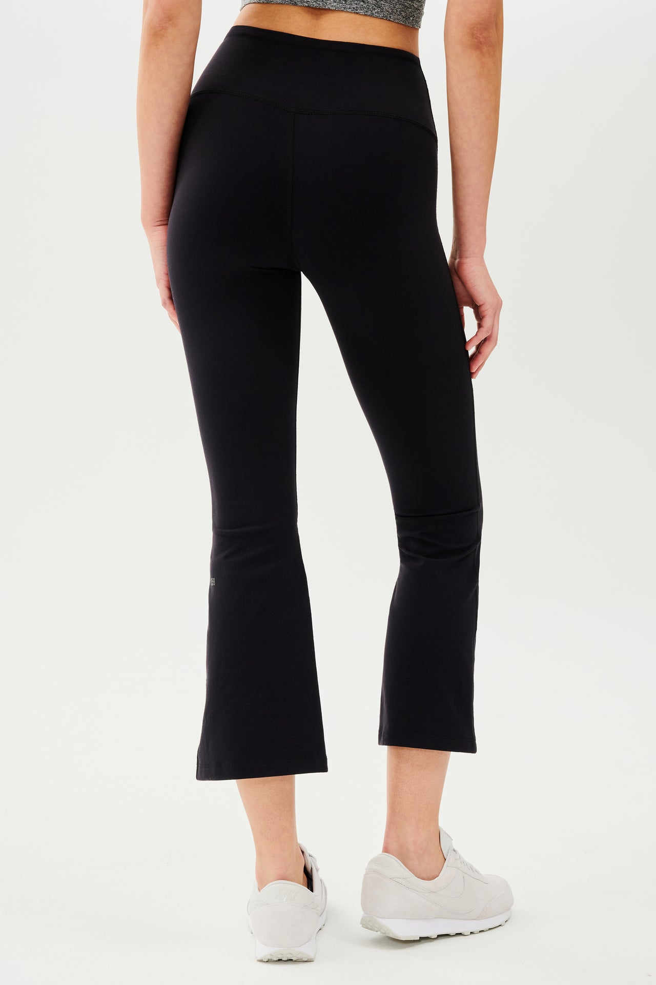 The back view of a woman wearing SPLITS59 Raquel High Waist Crop - Black leggings.