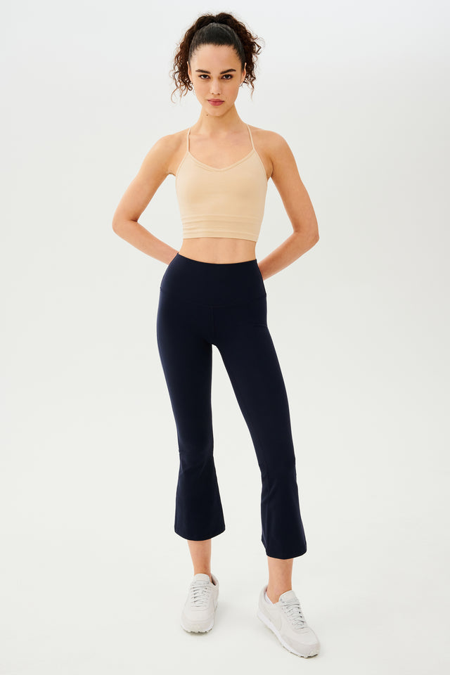 The model is wearing a beige Raquel High Waist Crop top and navy flared leggings made from 4-way stretch fabric, ideal for gym workouts by SPLITS59.