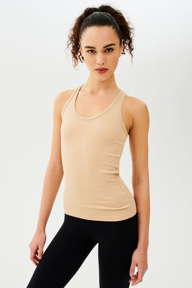 Side view of girl wearing a yellowish brown ribbed tank top and black leggings 