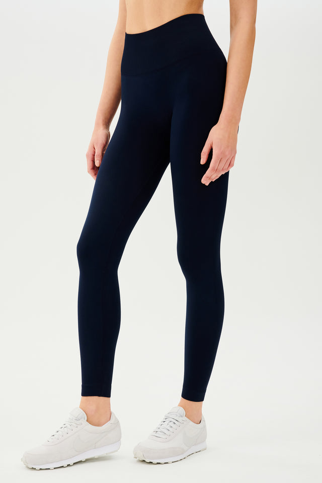 The back view of a woman wearing SPLITS59 Loren Seamless High Waist Full Length - Indigo leggings designed for enhanced gym workouts.