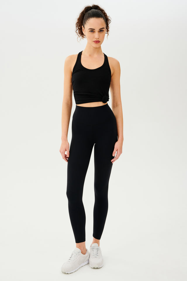 Full front view of girl wearing a black tank top and black leggings with white shoes