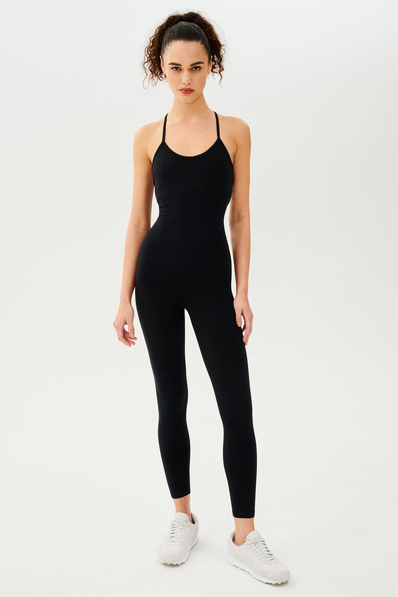 Full front view of  girl wearing black one piece with leggings and spaghetti straps