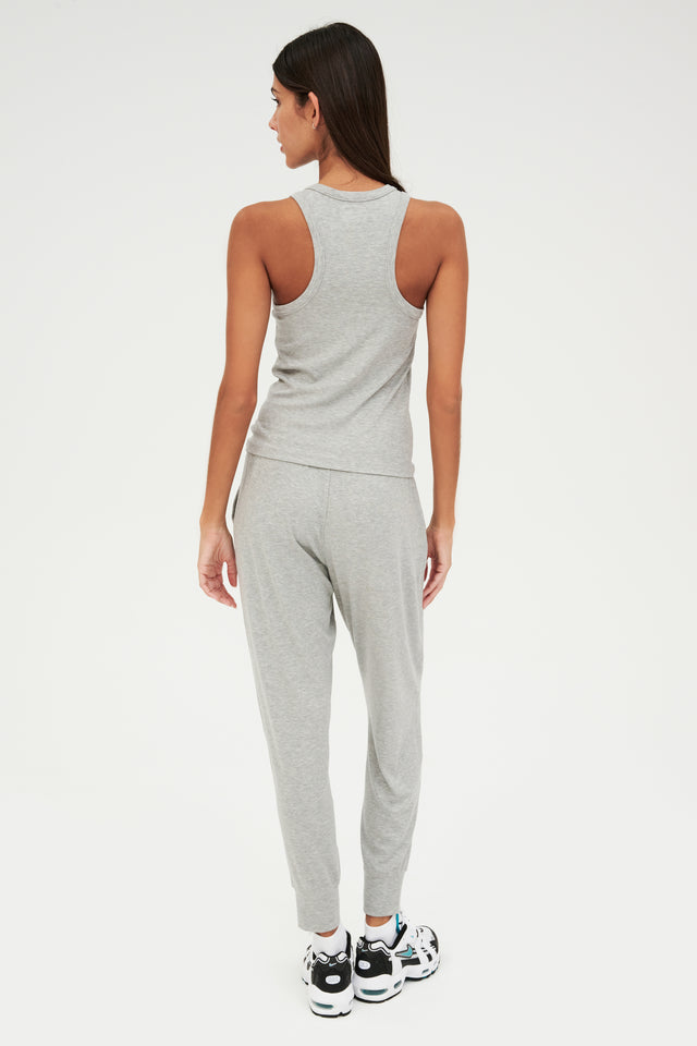 The back view of a woman wearing comfortable, grey ribbed Kiki Rib 7/8 Sweatpants by SPLITS59 and a tank top.