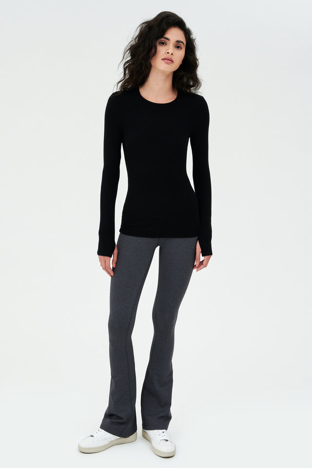 A woman wearing a SPLITS59 Louise Rib Long Sleeve - Black and grey leggings for gym workouts.