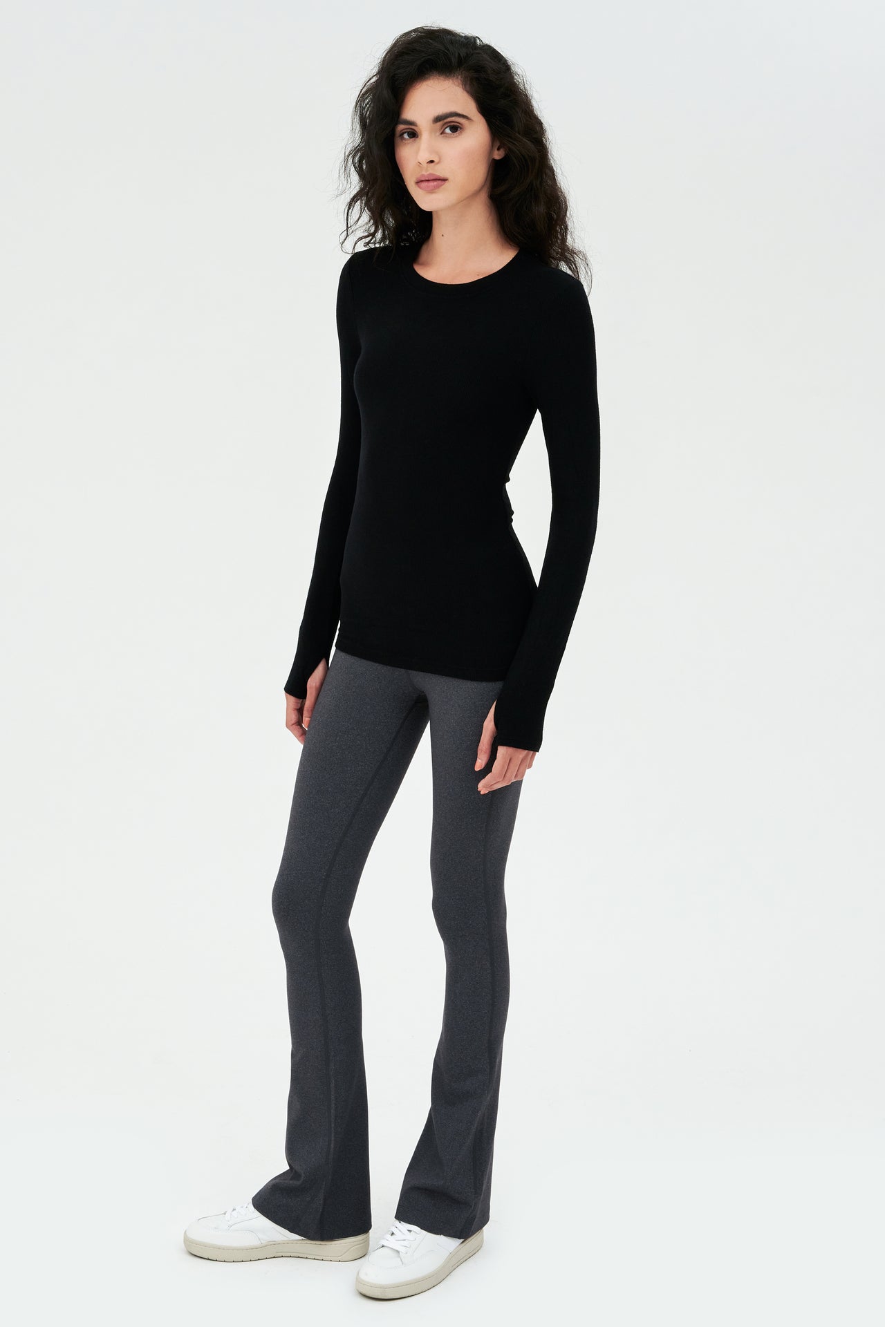 A woman wearing a SPLITS59 Louise Rib Long Sleeve in Black, perfect for gym workouts, and grey leggings.