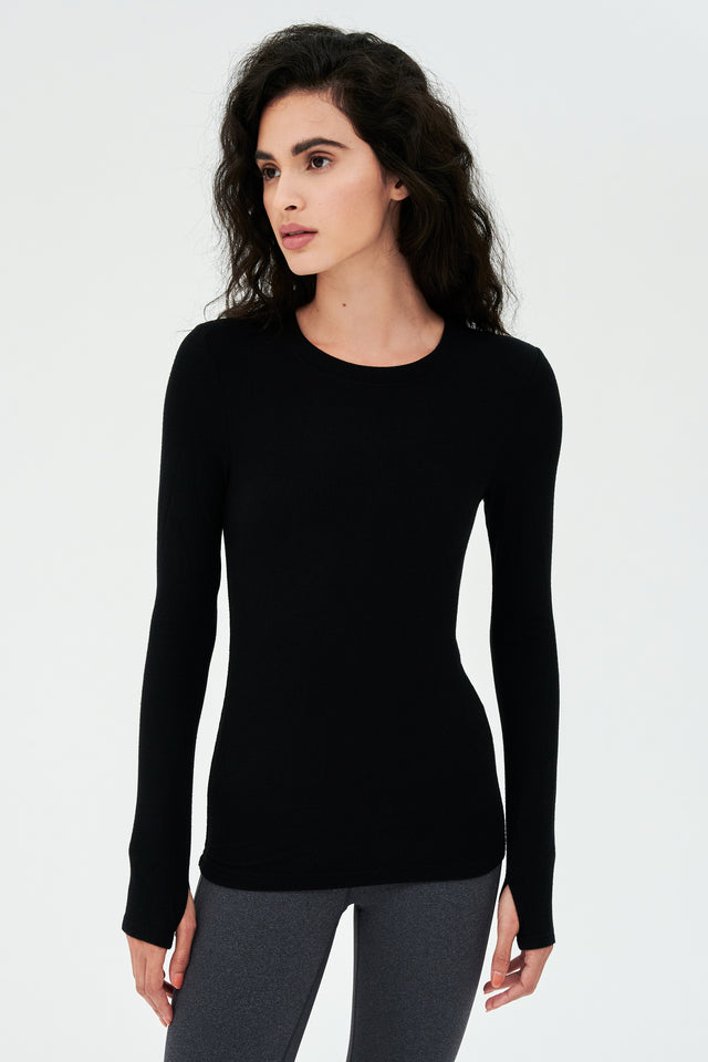 A woman layering a SPLITS59 Louise Rib Long Sleeve - Black shirt and leggings for gym workouts.