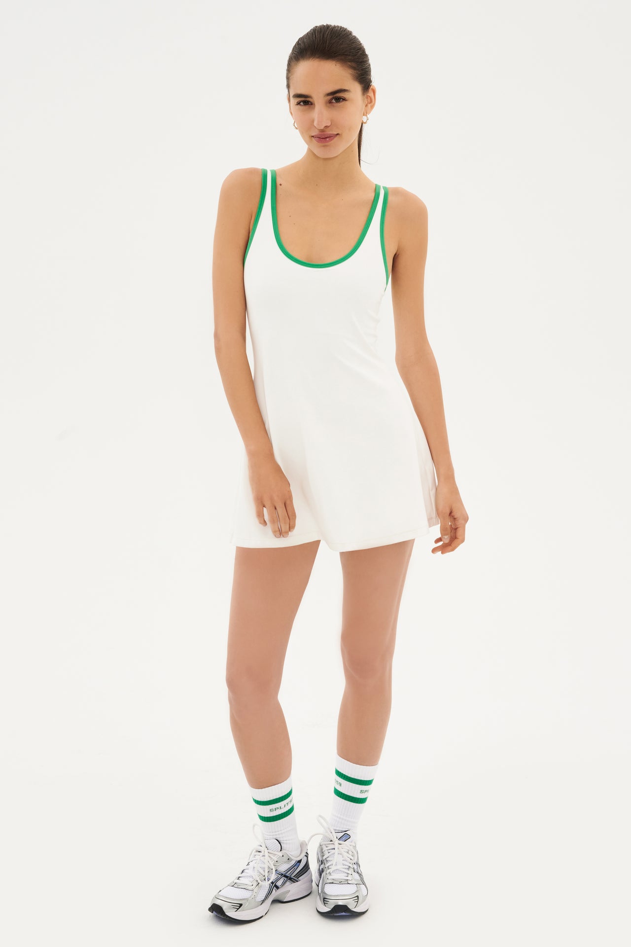 Full front view of girl wearing white loose mini tank top dress with green hem along neck and arms
